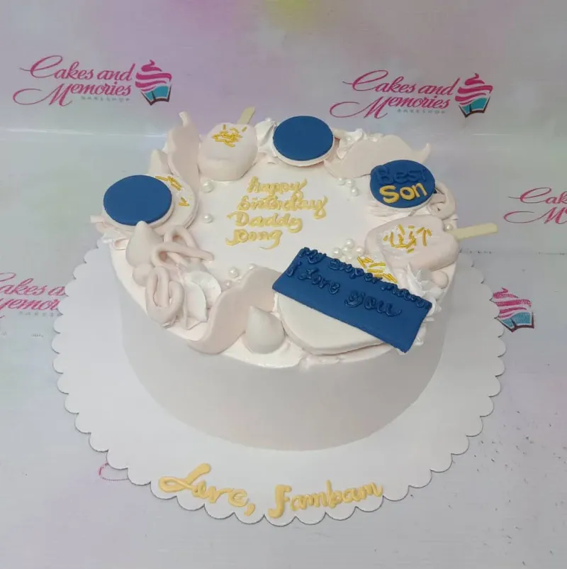 White minimalist birthday cake for a father with blue and white fondant decorations including popsicles, mustaches, and pearls. White minimalist birthday cake for a father with blue and white fondant decorations including popsicles, mustaches, and pearls.