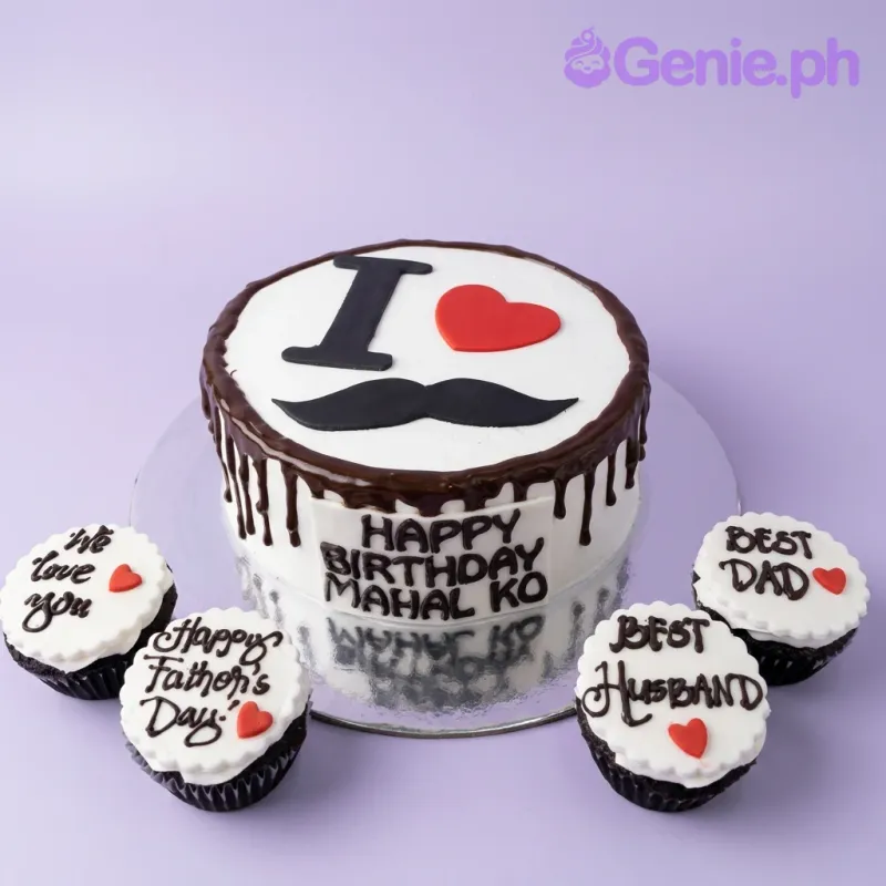 White 1-tier cake with chocolate drip, black mustache topper, and red heart, surrounded by four matching cupcakes for Father's Day. White 1-tier cake with chocolate drip, black mustache topper, and red heart, surrounded by four matching cupcakes for Father's Day.