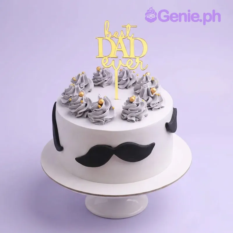 White minimalist cake for Father's Day featuring a gold Best Dad Ever topper, grey icing swirls with gold pearls, and black fondant mustaches. White minimalist cake for Father's Day featuring a gold Best Dad Ever topper, grey icing swirls with gold pearls, and black fondant mustaches.