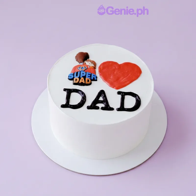 White single-tier cake with a Super Dad graphic topper, a red piped heart, and black piped DAD text White single-tier cake with a Super Dad graphic topper, a red piped heart, and black piped DAD text
