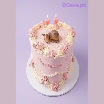 Pink heart-shaped birthday cake with a fawn figurine and two heart candles Pink heart-shaped birthday cake with a fawn figurine and two heart candles