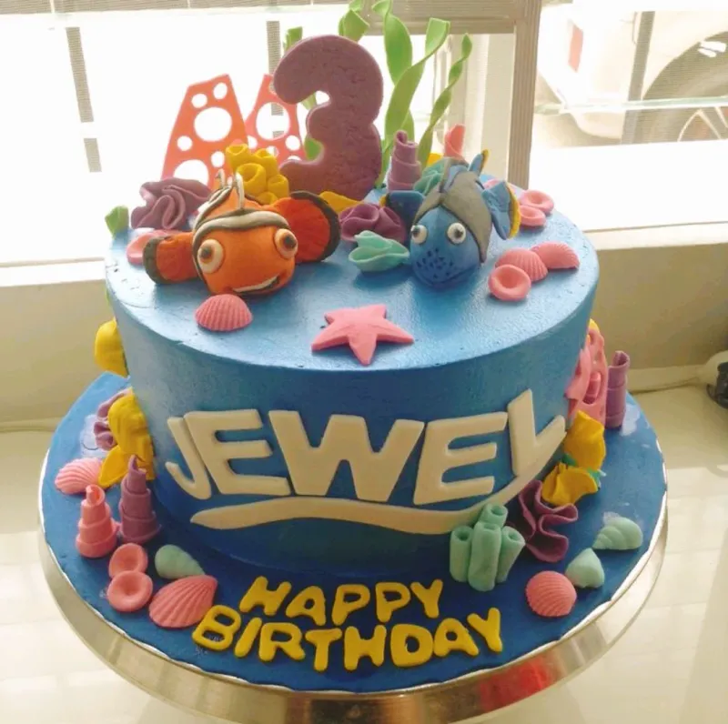 Blue Finding Nemo themed birthday cake with fondant Nemo and Dory figures, sea shells, and coral decorations. Blue Finding Nemo themed birthday cake with fondant Nemo and Dory figures, sea shells, and coral decorations.
