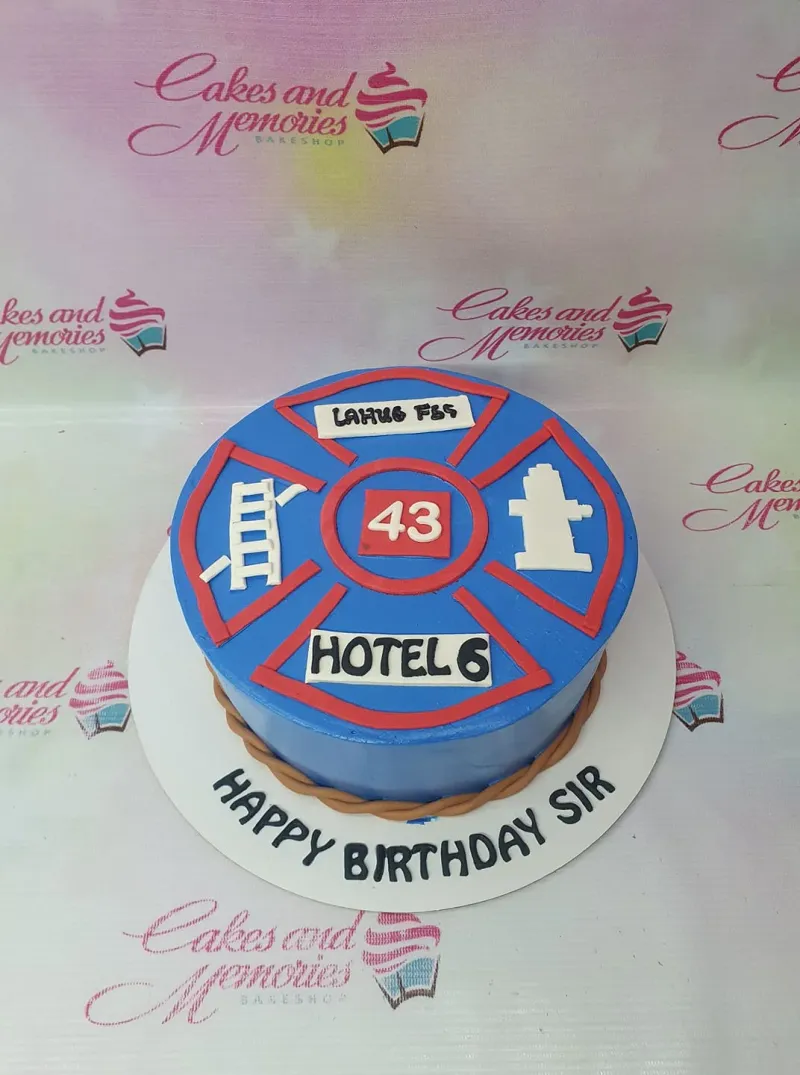A blue, red, white, and brown 1-Tier cake themed around Firefighter, featuring a Maltese cross emblem and fondant ladder, hydrant, and rope border. A blue, red, white, and brown 1-Tier cake themed around Firefighter, featuring a Maltese cross emblem and fondant ladder, hydrant, and rope border.
