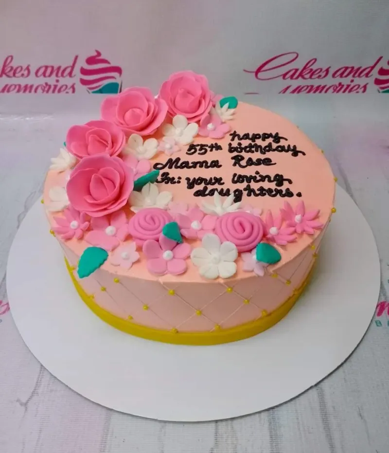 A pink 1-tier round cake with pink and white gumpaste roses, green leaves, yellow pearl sprinkles, and a black message. A pink 1-tier round cake with pink and white gumpaste roses, green leaves, yellow pearl sprinkles, and a black message.