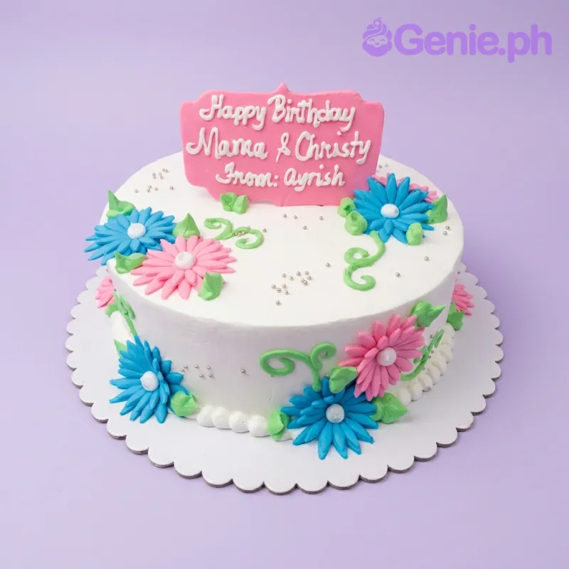 A white round 1-tier cake themed around Floral Birthday, featuring a pink message topper and pink and blue gumpaste flowers with green vines. A white round 1-tier cake themed around Floral Birthday, featuring a pink message topper and pink and blue gumpaste flowers with green vines.