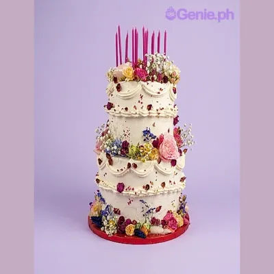 White 2-tier birthday cake with pink candles and assorted fresh flowers White 2-tier birthday cake with pink candles and assorted fresh flowers