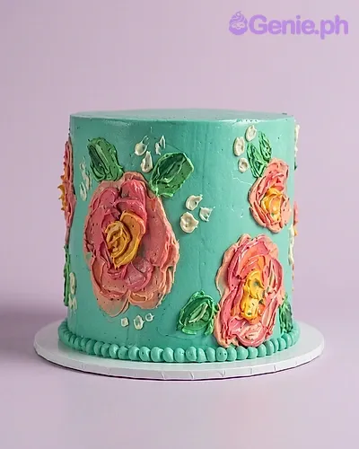 One tier teal cake with soft icing, featuring piped floral designs in pink, orange, yellow, and green, and a matching piped base border One tier teal cake with soft icing, featuring piped floral designs in pink, orange, yellow, and green, and a matching piped base border