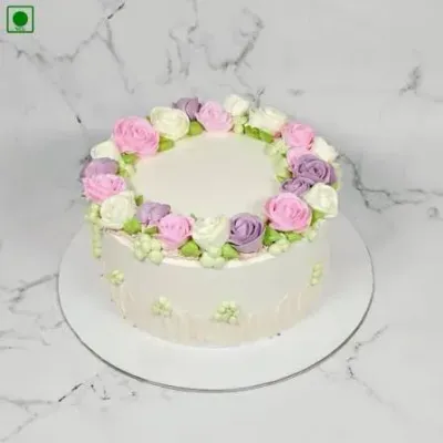 White 1-tier cake with smooth soft icing, piped floral wreath, and small green icing clusters White 1-tier cake with smooth soft icing, piped floral wreath, and small green icing clusters
