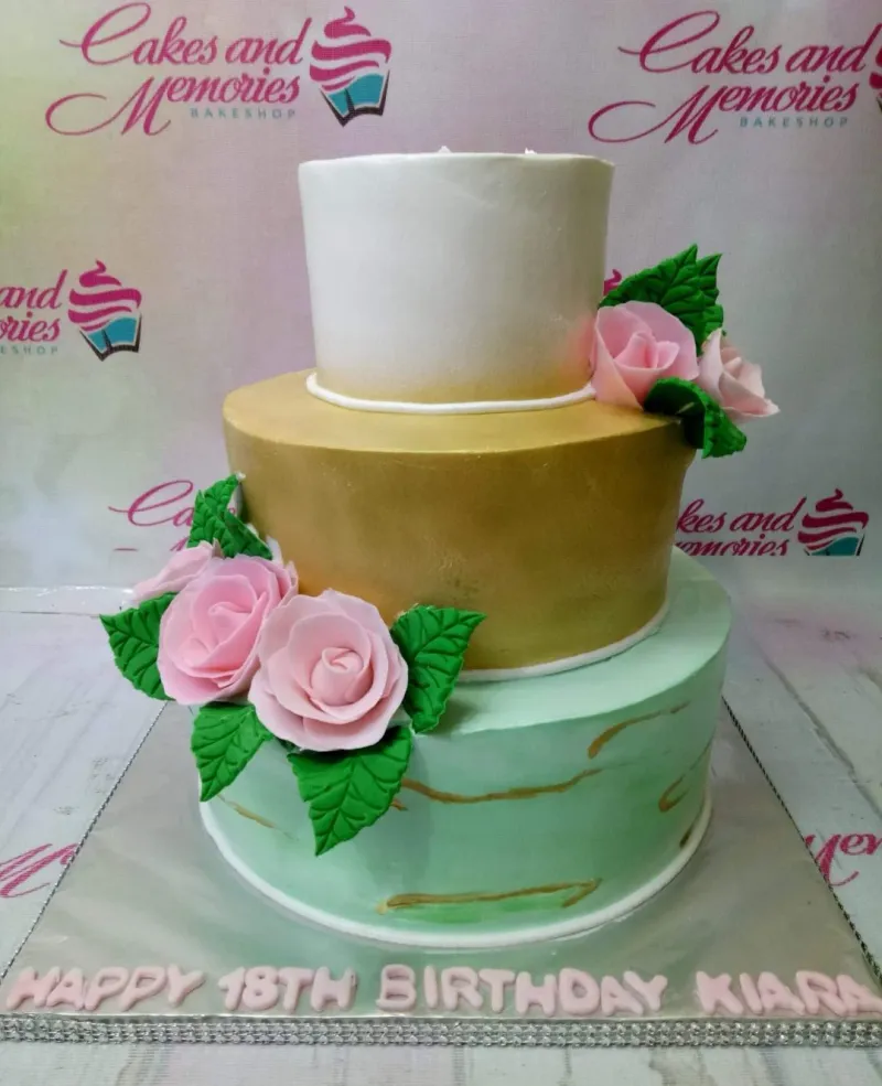 A white, gold, and mint green 3-tier cake, Floral Debut themed, with pink gumpaste roses, green leaves, and gold marble accents. A white, gold, and mint green 3-tier cake, Floral Debut themed, with pink gumpaste roses, green leaves, and gold marble accents.