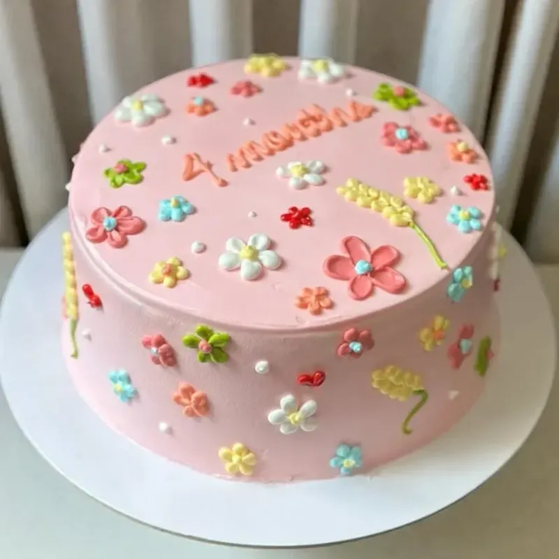 Pink minimalist cake decorated with colorful piped icing flowers and '4 months' message. Pink minimalist cake decorated with colorful piped icing flowers and '4 months' message.