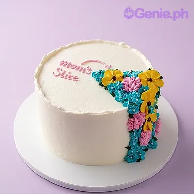 White single-tier cake with pink Mom's Slice message and colorful piped floral cascade on the side White single-tier cake with pink Mom's Slice message and colorful piped floral cascade on the side