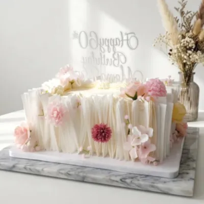 White rectangle cake with smooth soft icing, pink roses and white filler flowers, and a clear cardstock topper White rectangle cake with smooth soft icing, pink roses and white filler flowers, and a clear cardstock topper