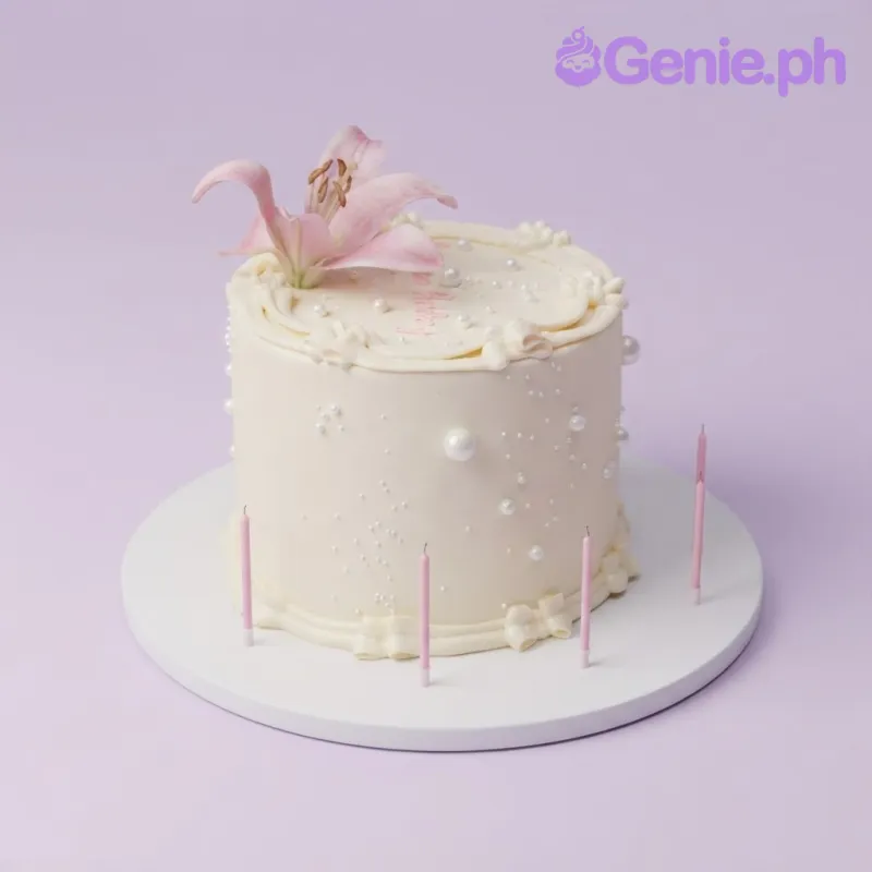 White 1-tier cake with soft icing, pink lily flowers, white sugar pearls, and piped script message White 1-tier cake with soft icing, pink lily flowers, white sugar pearls, and piped script message