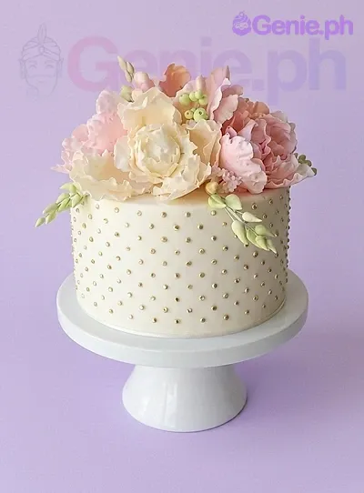 An ivory 1-tier cake themed Floral Peony, featuring large peach and cream gumpaste peonies, gold dragee polka dots, and light green buds. An ivory 1-tier cake themed Floral Peony, featuring large peach and cream gumpaste peonies, gold dragee polka dots, and light green buds.