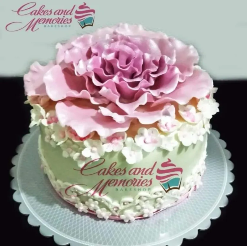 A light green 1-tier Floral Peony cake, featuring a large pink gumpaste peony and surrounding small white and pink flowers. A light green 1-tier Floral Peony cake, featuring a large pink gumpaste peony and surrounding small white and pink flowers.