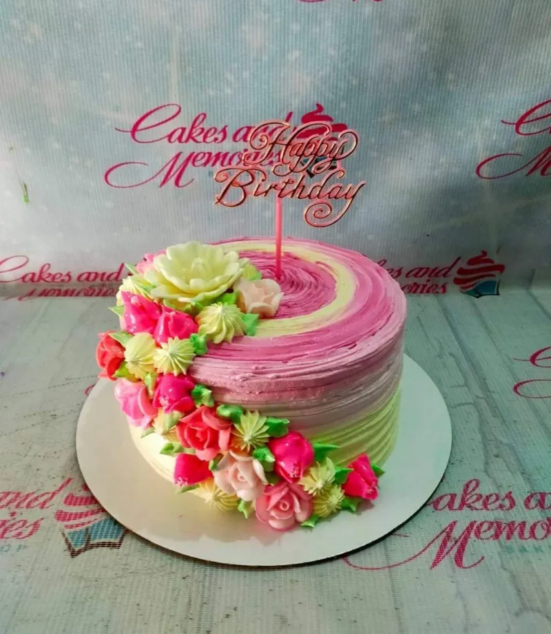A pink and yellow 1-tier cake, Floral Swirl themed, with a rose gold "Happy Birthday" topper and edible floral cascade. A pink and yellow 1-tier cake, Floral Swirl themed, with a rose gold "Happy Birthday" topper and edible floral cascade.