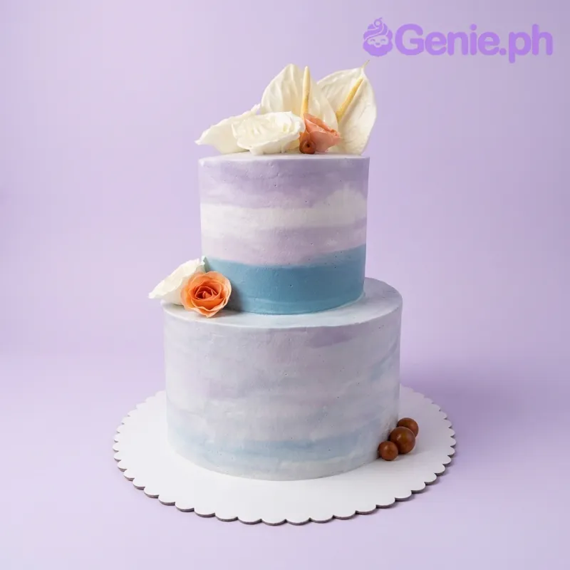 A blue, purple, and white two-tier cake themed around Floral Watercolor, featuring edible white and peach flowers and brown berry accents.
