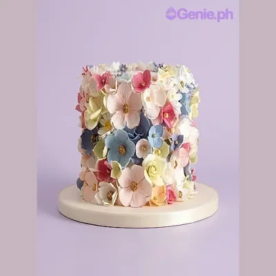 Floral cake design — 1 layer fondant cake in white — with pink sugar flowers, blue sugar flowers, and yellow and white sugar flowers Floral cake design — 1 layer fondant cake in white — with pink sugar flowers, blue sugar flowers, and yellow and white sugar flowers