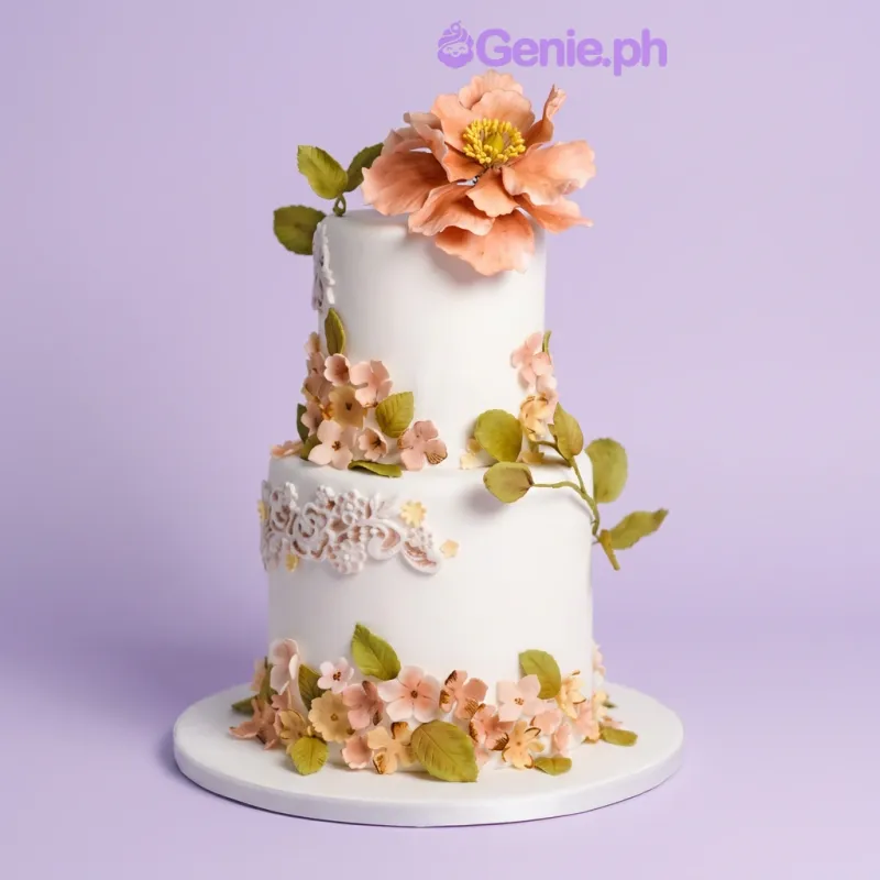 White 2-tier fondant cake with large peach gumpaste flower and small floral accents White 2-tier fondant cake with large peach gumpaste flower and small floral accents