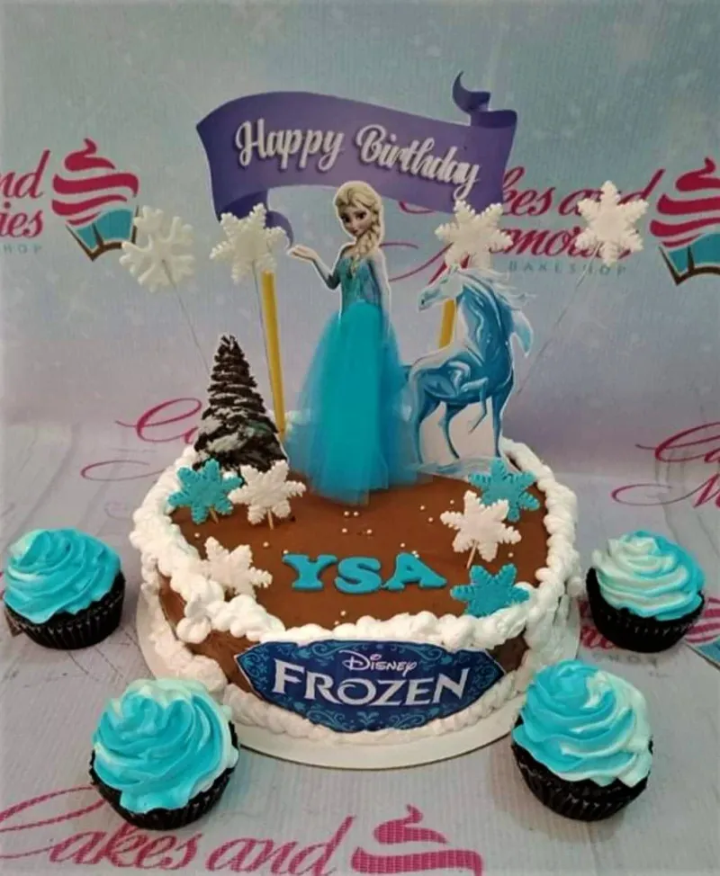 A chocolate brown 1 Tier cake themed around Disney Frozen, featuring Elsa and Nokk printouts, white and blue rosettes, and snowflake decorations. A chocolate brown 1 Tier cake themed around Disney Frozen, featuring Elsa and Nokk printouts, white and blue rosettes, and snowflake decorations.