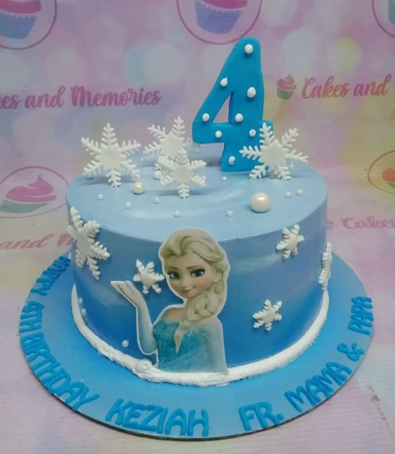 A blue and white single-tier Frozen Elsa cake with Elsa printout, blue number 4 topper, and white snowflakes. A blue and white single-tier Frozen Elsa cake with Elsa printout, blue number 4 topper, and white snowflakes.