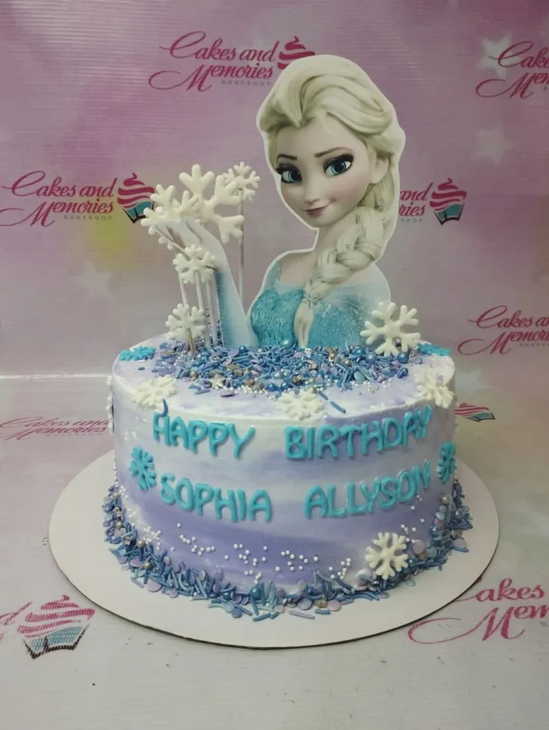 A white and purple Frozen Elsa cake, featuring an Elsa cutout, snowflakes, and sprinkles. A white and purple Frozen Elsa cake, featuring an Elsa cutout, snowflakes, and sprinkles.