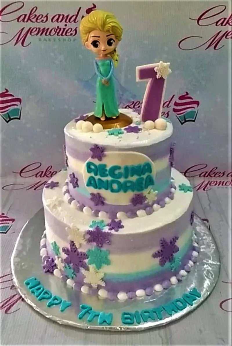 A white, purple, and blue two-tier cake themed around Frozen Elsa, featuring an Elsa figurine, a purple number seven, and various snowflake decorations. A white, purple, and blue two-tier cake themed around Frozen Elsa, featuring an Elsa figurine, a purple number seven, and various snowflake decorations.