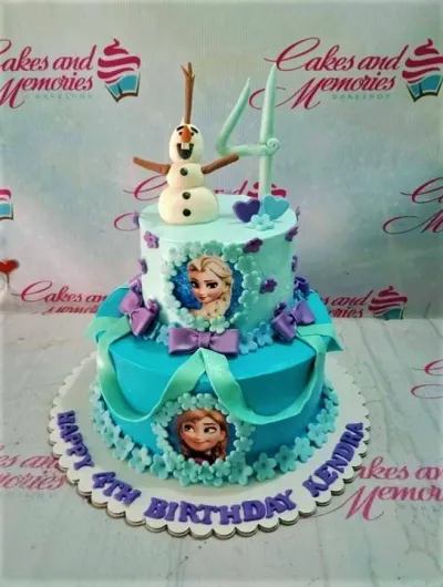 A light blue and teal two-tier cake themed around Frozen, featuring an Olaf figure, number 4 topper, Elsa and Anna printouts, and decorative icing. A light blue and teal two-tier cake themed around Frozen, featuring an Olaf figure, number 4 topper, Elsa and Anna printouts, and decorative icing.