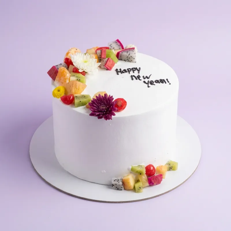 White bento cake with fresh fruit and flower toppings, featuring a Happy New Year message and a separate anniversary topper. White bento cake with fresh fruit and flower toppings, featuring a Happy New Year message and a separate anniversary topper.
