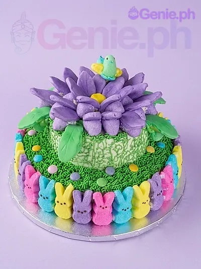 A green and multi-colored two-tier Garden Peeps cake, featuring a large purple flower, small bird, and colorful marshmallow bunnies. A green and multi-colored two-tier Garden Peeps cake, featuring a large purple flower, small bird, and colorful marshmallow bunnies.