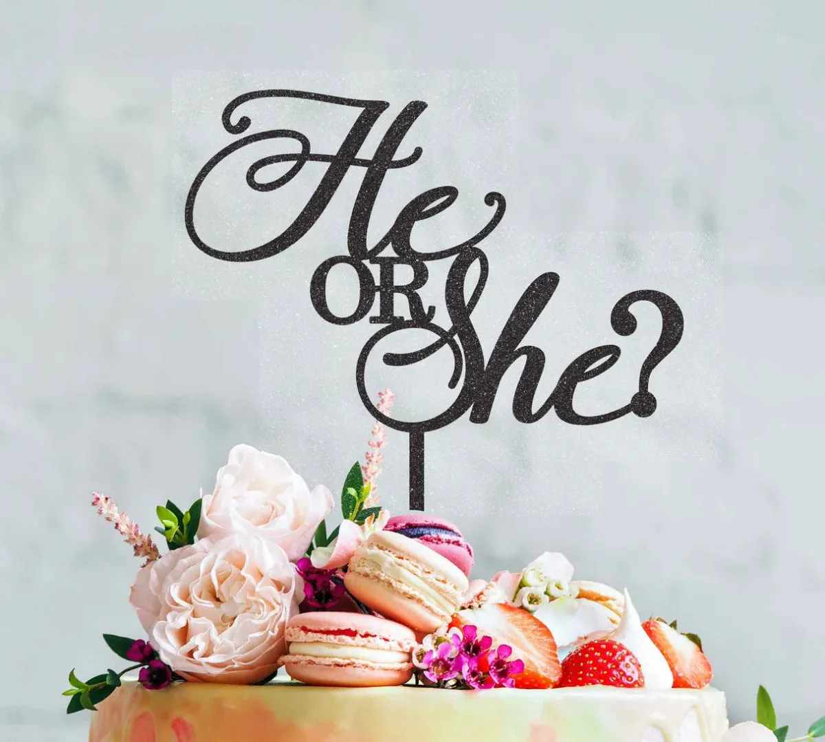 A 1-tier Gender Reveal cake with a black glitter 'He or She?' topper, macarons, fresh roses, and strawberries. A 1-tier Gender Reveal cake with a black glitter 'He or She?' topper, macarons, fresh roses, and strawberries.