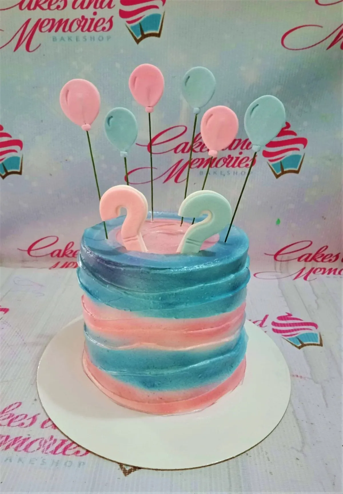 A pink and blue 1 Tier cake themed around Gender Reveal, featuring pink and blue fondant question marks and fondant balloons. A pink and blue 1 Tier cake themed around Gender Reveal, featuring pink and blue fondant question marks and fondant balloons.