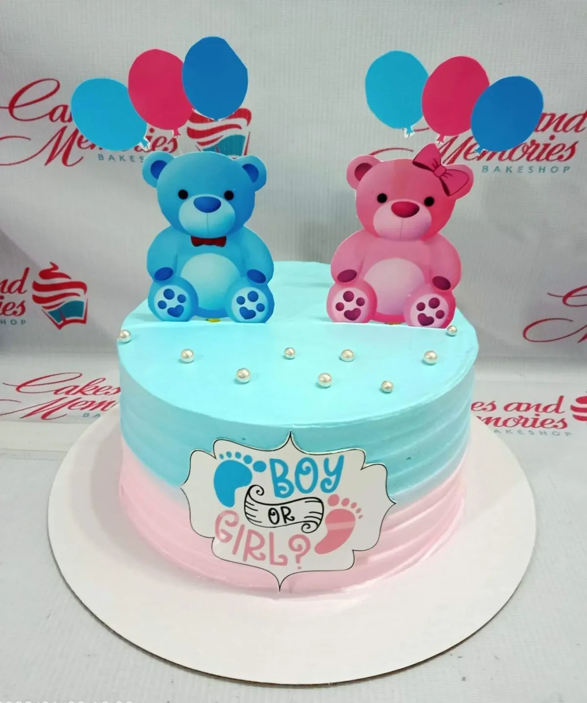 A blue and pink 1 Tier cake themed around Gender Reveal, featuring blue and pink bear and balloon printouts, white pearls, and a "Boy or Girl?" message. A blue and pink 1 Tier cake themed around Gender Reveal, featuring blue and pink bear and balloon printouts, white pearls, and a "Boy or Girl?" message.