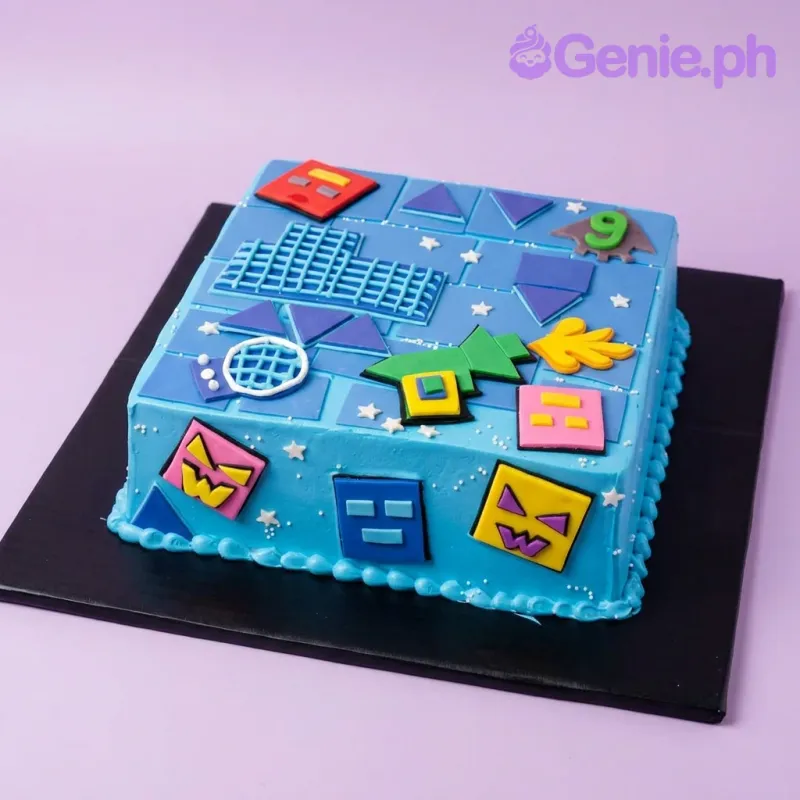 A blue square Geometry Dash themed cake, featuring a green ship, colorful square face icons, a green number nine, and white star sprinkles. A blue square Geometry Dash themed cake, featuring a green ship, colorful square face icons, a green number nine, and white star sprinkles.