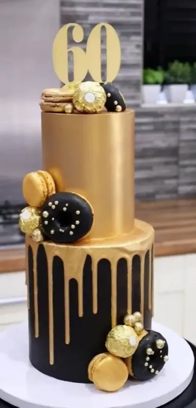 Gold 2-tier fondant cake with a drip effect, number sixty topper, gold macarons, and black glazed donuts Gold 2-tier fondant cake with a drip effect, number sixty topper, gold macarons, and black glazed donuts