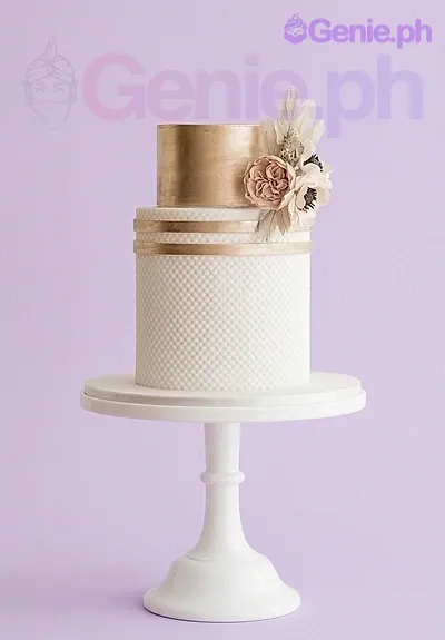 A white and gold 2 Tier Fondant cake themed around Gold Floral, featuring pink peony and ivory flowers and gold fondant bands. A white and gold 2 Tier Fondant cake themed around Gold Floral, featuring pink peony and ivory flowers and gold fondant bands.