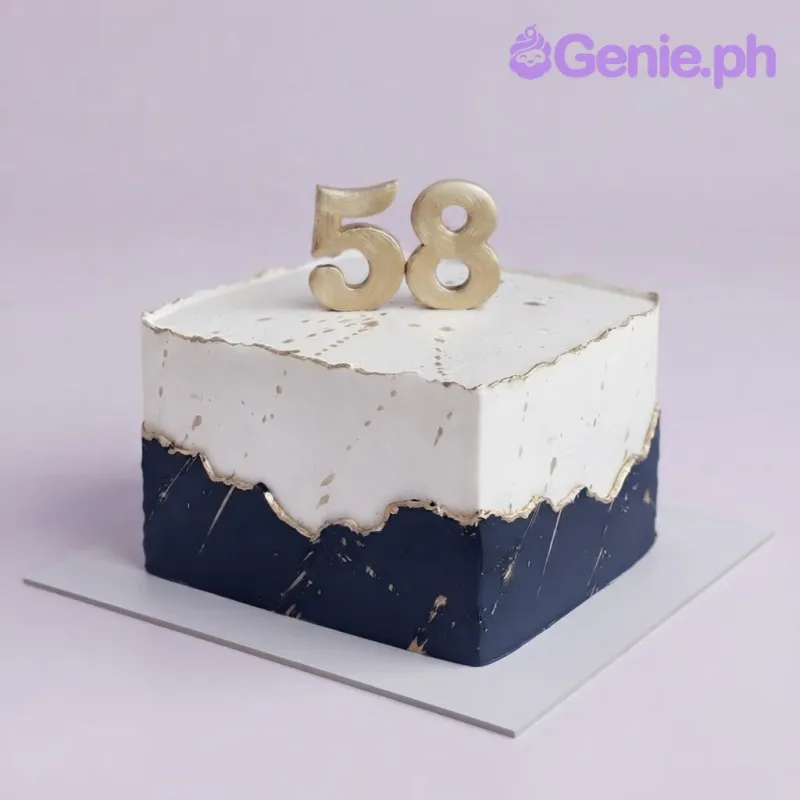 Square white and navy blue cake with gold splatters and a gold number 58 topper Square white and navy blue cake with gold splatters and a gold number 58 topper