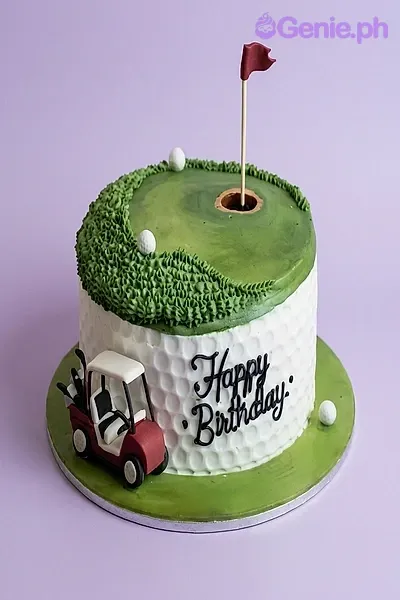 A green and white 1 Tier cake themed around Golf, featuring a golf cart figurine, a red golf flag, piped green grass, and white golf balls. A green and white 1 Tier cake themed around Golf, featuring a golf cart figurine, a red golf flag, piped green grass, and white golf balls.