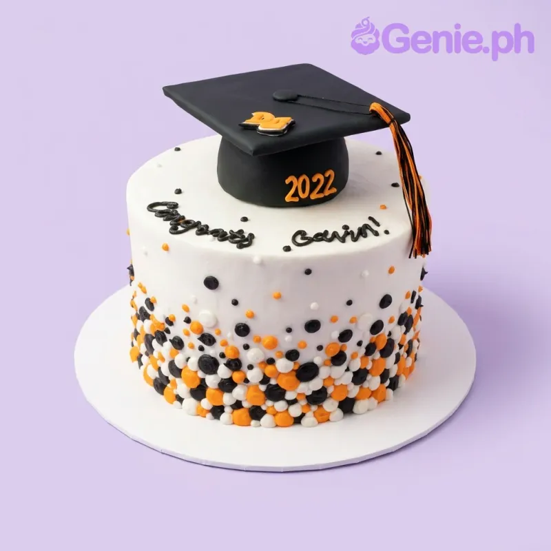 A white 1-tier cake themed around Graduation, featuring a black graduation cap, '2022' numbers, and icing dots. A white 1-tier cake themed around Graduation, featuring a black graduation cap, '2022' numbers, and icing dots.