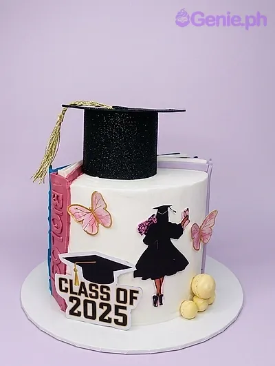 White graduation cake for Class of 2025 featuring a black graduation cap topper, pink butterflies, and a silhouette of a graduate. White graduation cake for Class of 2025 featuring a black graduation cap topper, pink butterflies, and a silhouette of a graduate.