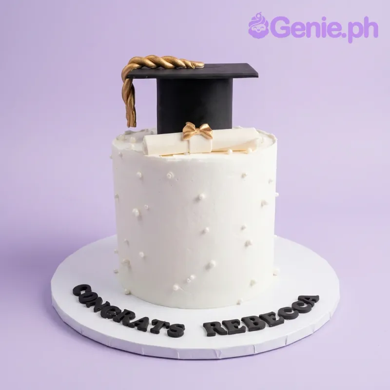 A white 1-tier tall cake themed around Graduation, featuring a black cap, a white diploma with a gold bow, white pearl sprinkles, and 'CONGRATS REBECCA' text. A white 1-tier tall cake themed around Graduation, featuring a black cap, a white diploma with a gold bow, white pearl sprinkles, and 'CONGRATS REBECCA' text.