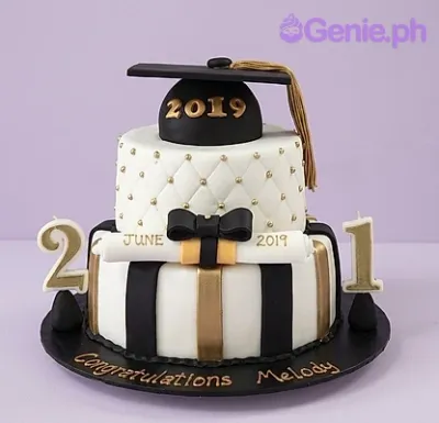 Two-tier graduation cake with black and white stripes, gold accents, a fondant graduation cap, and a diploma topper. Two-tier graduation cake with black and white stripes, gold accents, a fondant graduation cap, and a diploma topper.