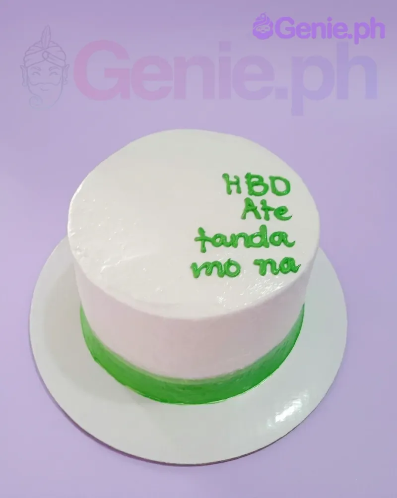 A white and green 1-tier minimalist cake, featuring a green icing border at the base and a green piped message on top. A white and green 1-tier minimalist cake, featuring a green icing border at the base and a green piped message on top.