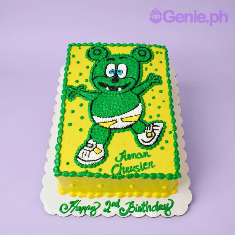 A yellow and green rectangle Gummy Bear themed cake, featuring a piped green Gummy Bear character and decorative icing borders. A yellow and green rectangle Gummy Bear themed cake, featuring a piped green Gummy Bear character and decorative icing borders.