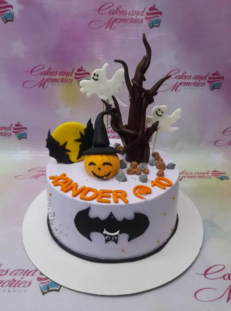 A light purple 1-tier Halloween cake with a pumpkin, spooky tree, white ghosts, black bat silhouettes, and a yellow moon. A light purple 1-tier Halloween cake with a pumpkin, spooky tree, white ghosts, black bat silhouettes, and a yellow moon.
