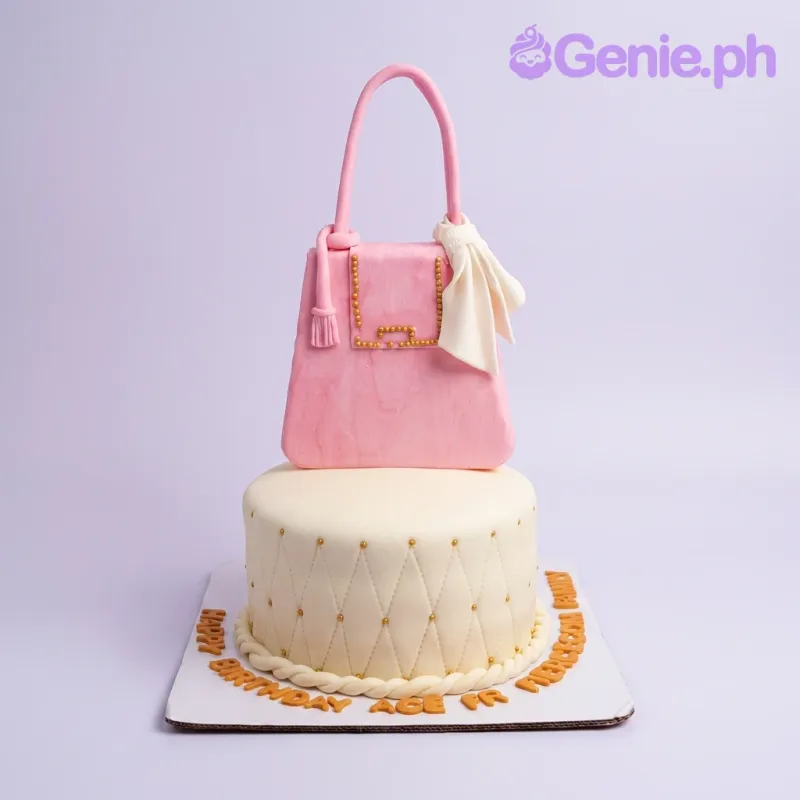 Two-tier pink and ivory designer handbag cake with gold quilted details and a large pink fondant purse topper. Two-tier pink and ivory designer handbag cake with gold quilted details and a large pink fondant purse topper.