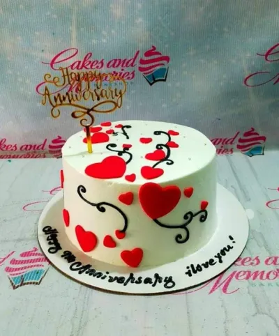 A white 1-tier Heart Anniversary cake, featuring a gold 'Happy Anniversary' topper, red hearts, and black icing swirls. A white 1-tier Heart Anniversary cake, featuring a gold 'Happy Anniversary' topper, red hearts, and black icing swirls.