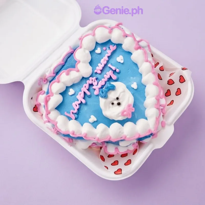 Blue heart-shaped bento cake with white and pink piped borders and a small white character topper Blue heart-shaped bento cake with white and pink piped borders and a small white character topper