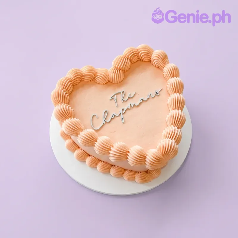 One tier heart cake with peach soft icing, a cardstock topper, and piped icing borders One tier heart cake with peach soft icing, a cardstock topper, and piped icing borders
