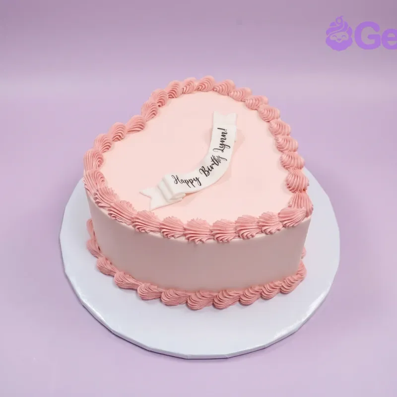 Pink heart-shaped cake with a Happy Birthday banner topper and piped border Pink heart-shaped cake with a Happy Birthday banner topper and piped border